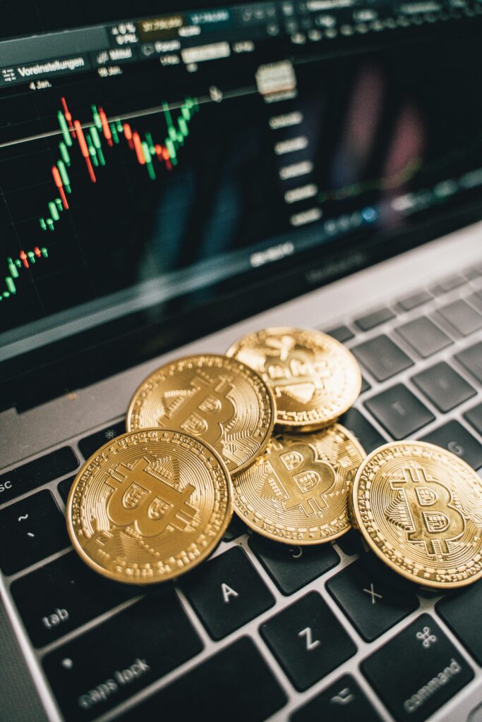 pexels-photo-6770845-6770845 Close-up of gold Bitcoin coins on a laptop keyboard with a stock chart, symbolizing cryptocurrency market analysis.